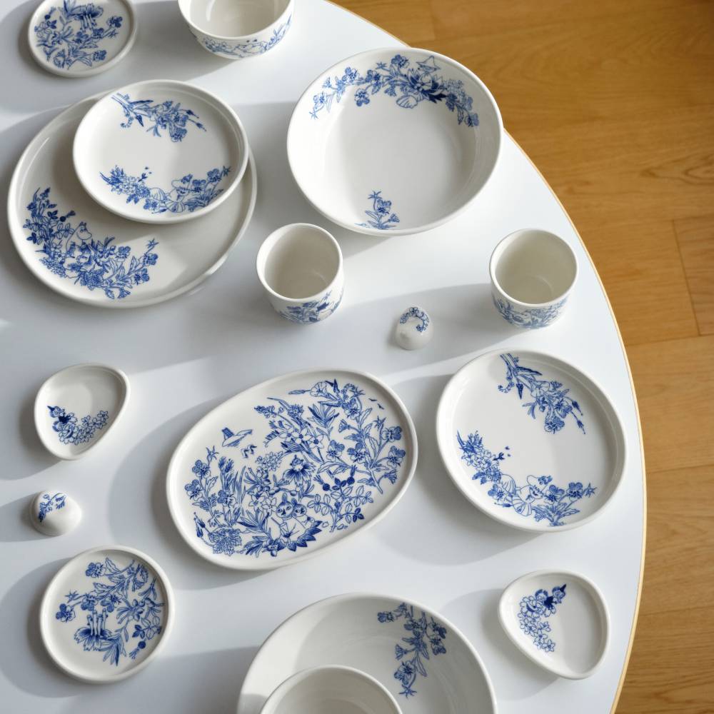 Set of white ceramic dishes with blue floral patterns on a white surface.